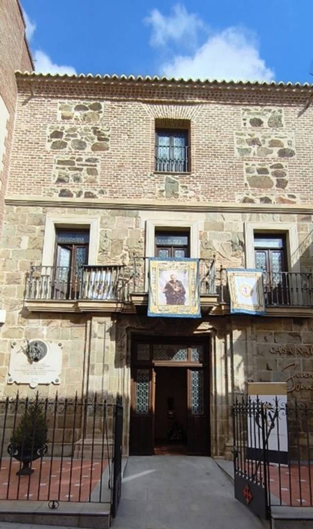 Edificio histórico con una fachada de piedra y ladrillo, adornado con banderas.