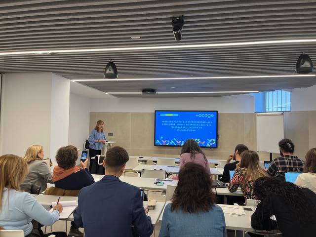 Una presentación en un aula moderna con un presentador frente a una pantalla.