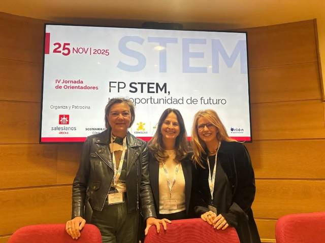 Tres mujeres sonrientes posan frente a un cartel sobre la jornada IV de Orientadores en el ámbito STEM.