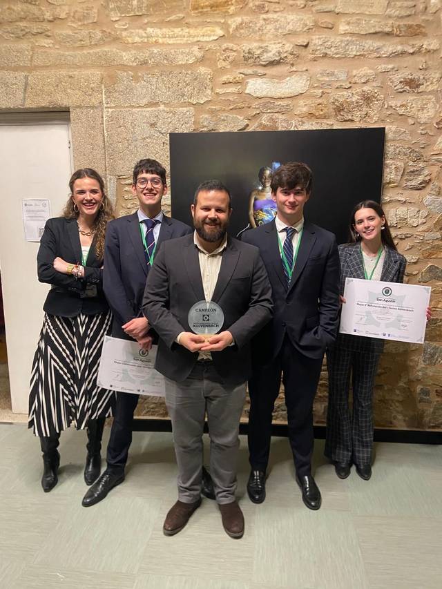 Un grupo de cuatro personas posando en un evento con un premio y diplomas.