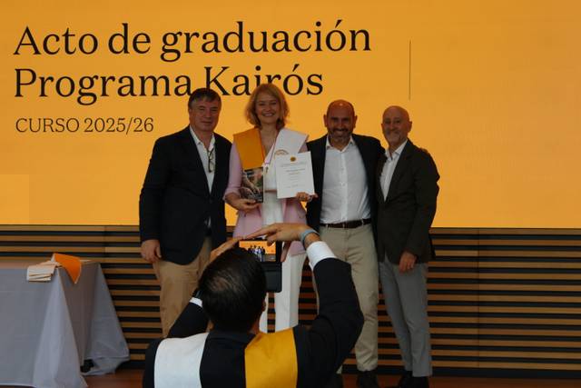Un grupo de cuatro personas sonríen en un acto de graduación del Programa Kairós.
