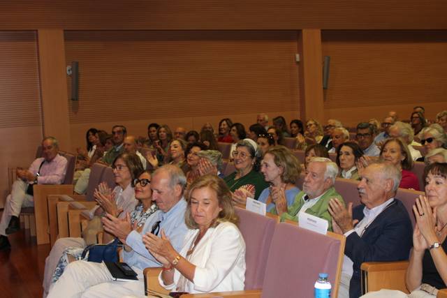 Un grupo de personas aplaudiendo en un auditorio durante un evento.