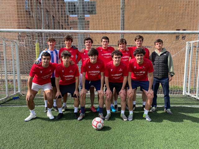Un grupo de adolescentes posando en un campo de fútbol con camisetas rojas.
