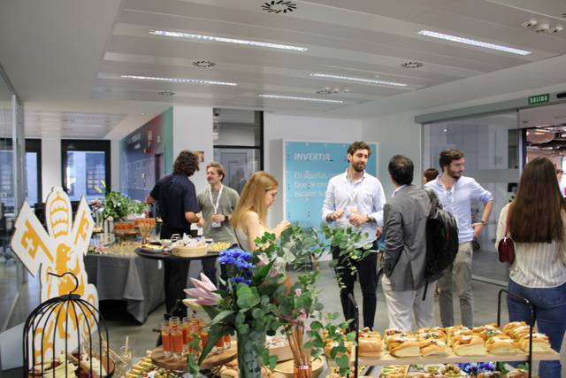 Una reunión empresarial con personas conversando y una mesa de catering en primer plano.