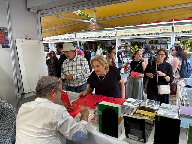 Jorge Fernández Úbeda firma ejemplares de su obra 'La era de la fraternidad' desde dentro de la caseta de la Universidad Pontificia Comillas en la 84ª Feria del Libro de Madrid
