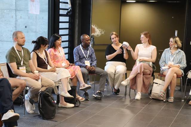 Un grupo de personas sentadas en un círculo durante una reunión o taller.