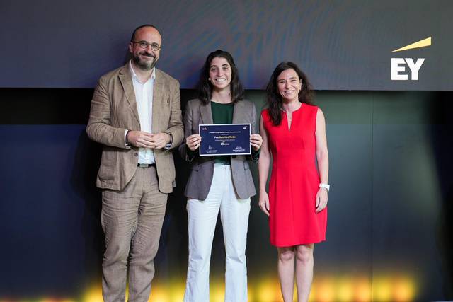 Three people, two women and one man, smiling while holding a plaque at an EY award event.