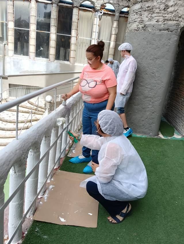 Un grupo de personas está pintando una barandilla en un balcón.