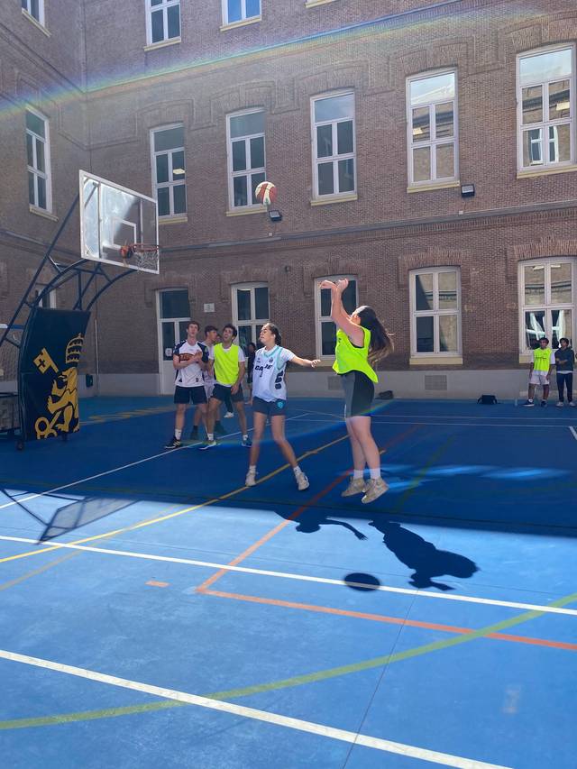 Un grupo de jóvenes juega al baloncesto en una cancha al aire libre.