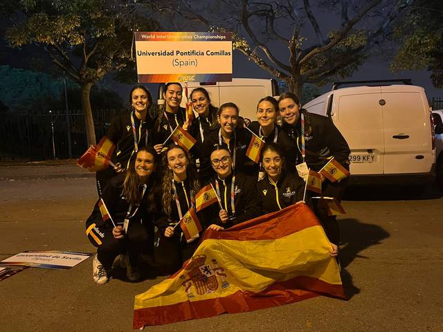 Un grupo de once mujeres sonrientes, vestidas con chaquetas negras, sosteniendo banderas de España y celebrando un evento deportivo.
