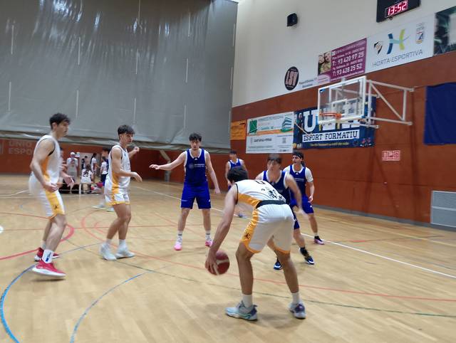 Un grupo de jugadores de baloncesto compiten en un partido en una cancha cubierta.