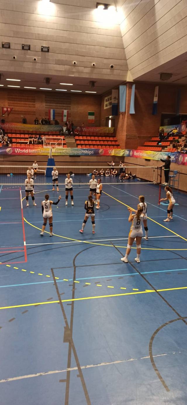 Un partido de voleibol en un polideportivo con varias jugadoras en acción.