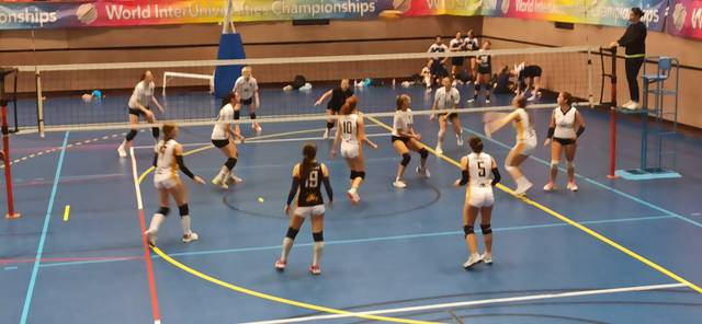 Un grupo de jugadoras de voleibol compite en una cancha durante un campeonato.