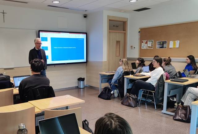 Un profesor está dando una clase a un grupo de estudiantes en un aula moderna.