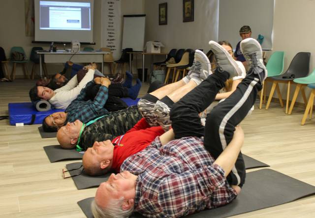 Un grupo de personas está realizando ejercicios en el suelo en una sala de entrenamiento.