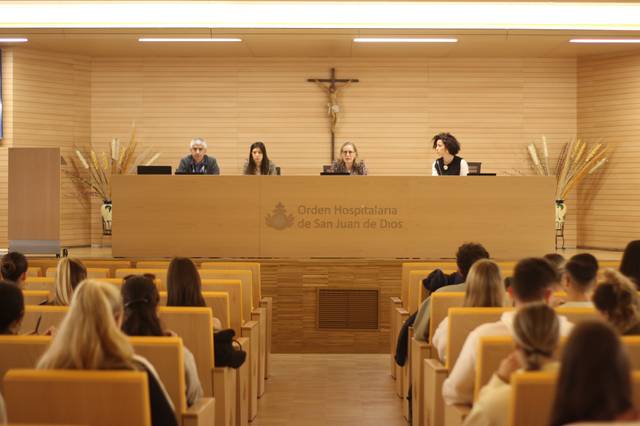 Una conferencia o charla se está llevando a cabo en un salón con sillas dispuestas para los asistentes.