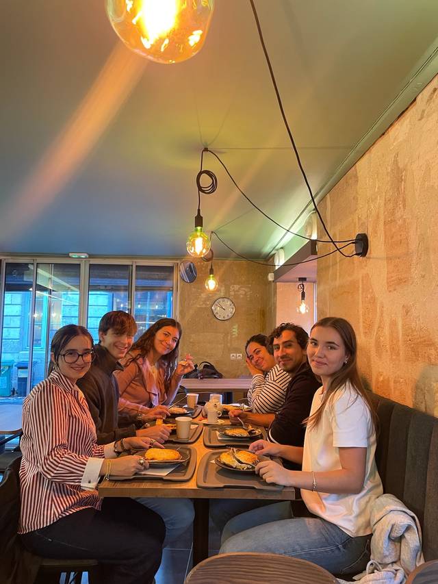 Un grupo de seis personas disfrutando de un desayuno en un café moderno.