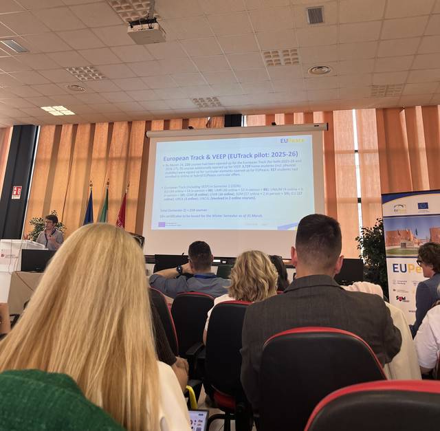 Una presentación en un evento con un proyector mostrando información sobre el programa European Track y VEIPR.