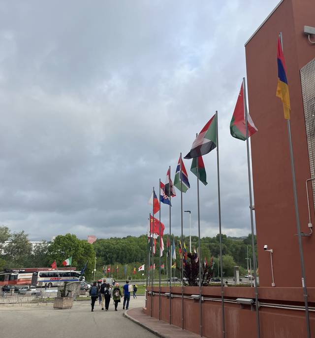 Una calle con banderas de diferentes países y un grupo de personas caminando.