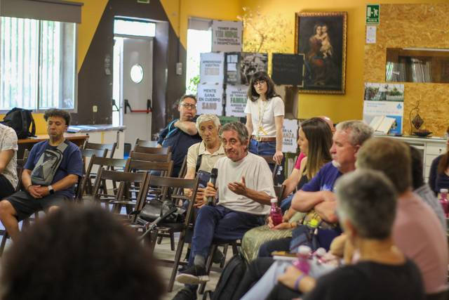 Una reunión en un espacio comunitario donde varias personas están sentadas y participando en una discusión.