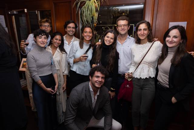 A group of ten people posing for a photo at a social gathering, smiling and standing closely together in an indoor setting.