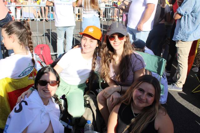 Cuatro jóvenes sonríen mientras disfrutan de un evento al aire libre.