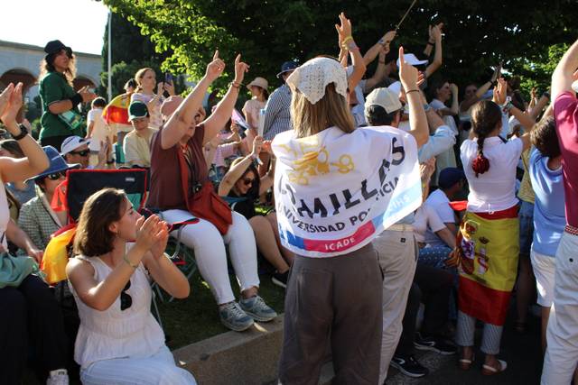 Un grupo de personas celebra y aplaude en un evento al aire libre, mostrando banderas y un ambiente festivo.