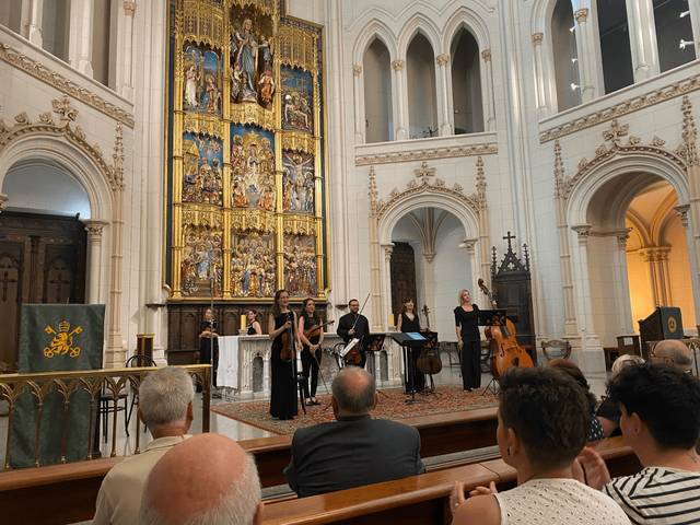 Una orquesta actuando en un entorno arquitectónico religioso.