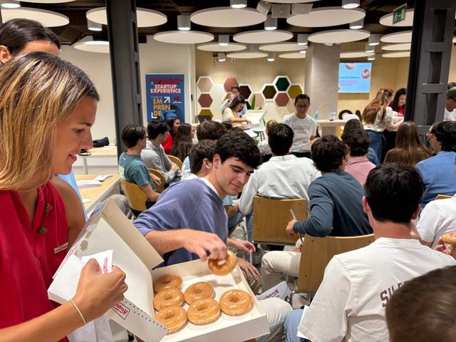 Un grupo de jóvenes en un evento, disfrutando y compartiendo donas en un ambiente colaborativo.