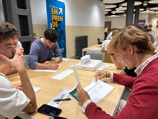 Un grupo de jóvenes están sentados en una mesa trabajando en un proyecto académico.