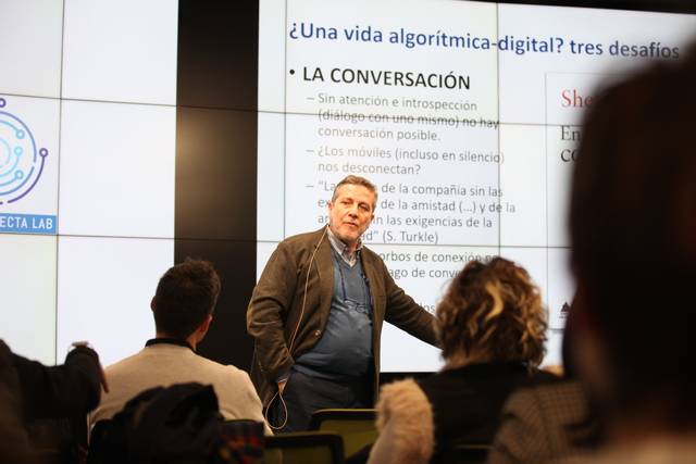 Un hombre de pie frente a una audiencia durante una presentación sobre desafíos digitales y algorítmicos.