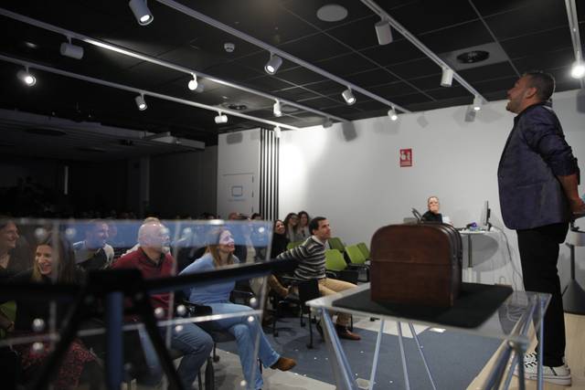 Un hombre está de pie dando una presentación frente a un grupo de personas sentadas en una sala de conferencias.