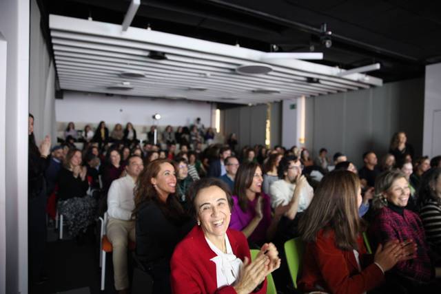 Un grupo de personas sentadas en una sala de conferencias aplaudiendo con entusiasmo.