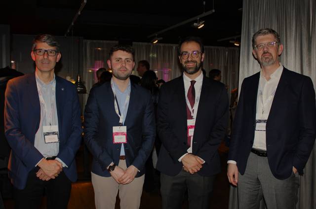 Cuatro hombres de negocios posando para una fotografía en un evento profesional.