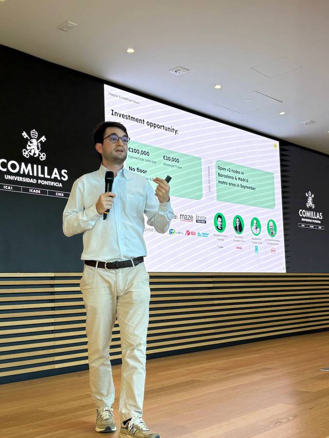 Un presentador expone una oportunidad de inversión en un evento en la universidad.