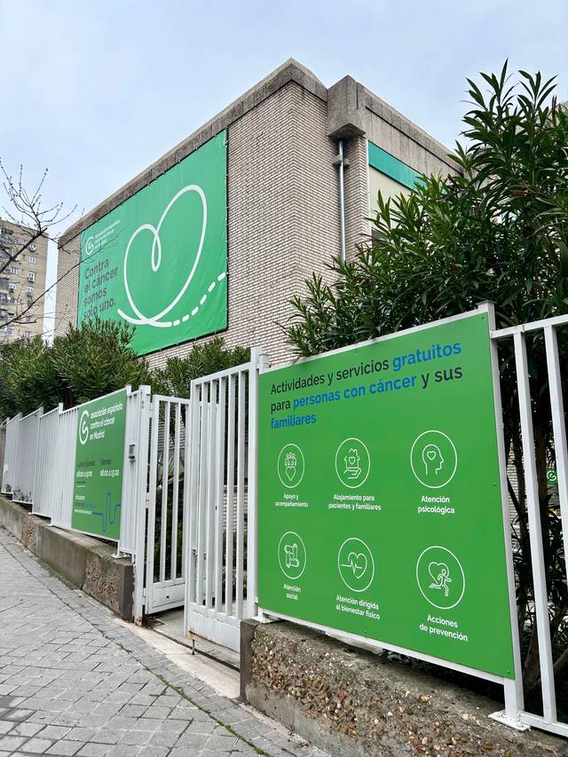 Edificio con un cartel que ofrece servicios gratuitos para personas con cáncer y sus familias.