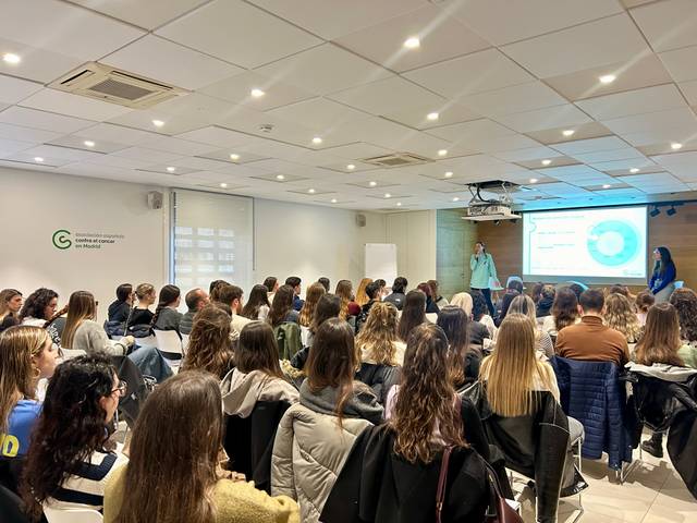 Una sala llena de estudiantes prestando atención a una presentación.