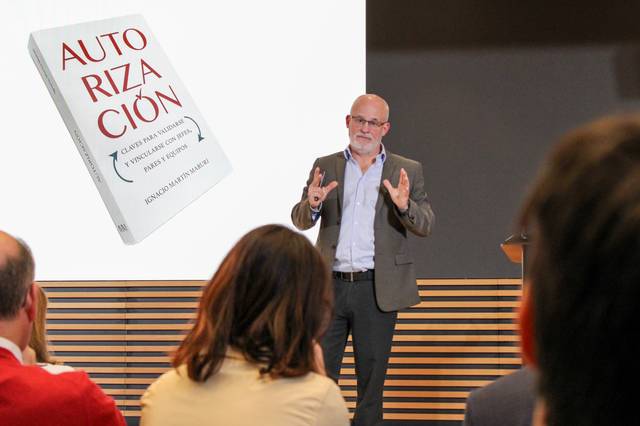 Un conferencista está presentando un libro titulado 'Autorización'.