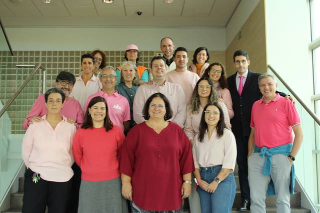 Grupo de personas vestidas de rosa posando en una escalera.