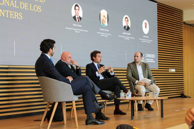 Un panel de discusión con cuatro ponentes en un ambiente moderno y profesional.
