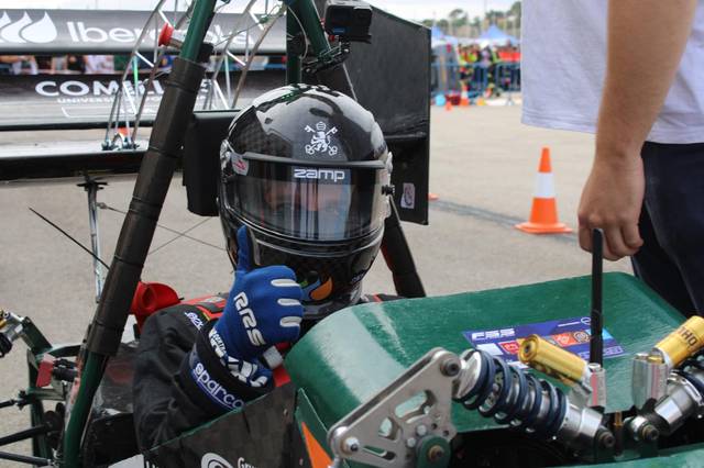 Piloto de automovilismo en su vehículo de competición preparándose para una carrera.
