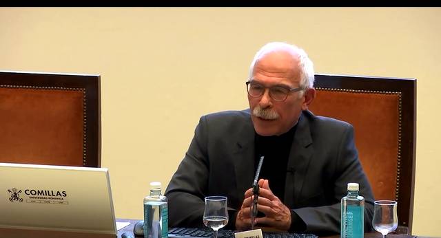 Un hombre con barba y gafas hablando en un evento en la Universidad Pontificia Comillas.