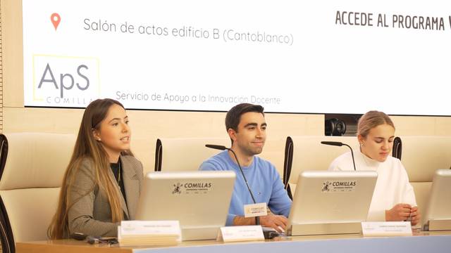 Panel de presentación en un salón de actos con tres ponentes en una mesa.