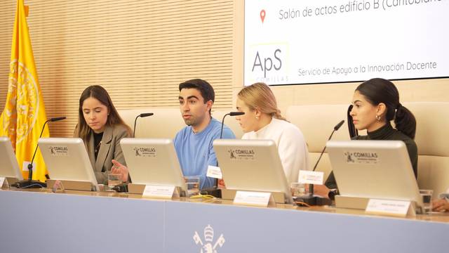 Una mesa de debate con cuatro personas hablando frente a un público en un salón de actos.