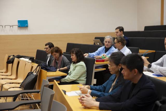 Un grupo de personas sentadas en un aula, prestando atención a una presentación.