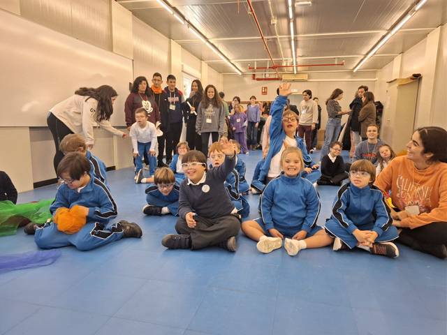 Un grupo de niños y adultos participan en una actividad en un espacio interior.