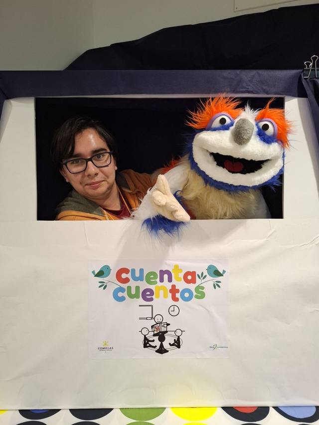 Un narrador de cuentos muestra una marioneta desde un escenario improvisado.