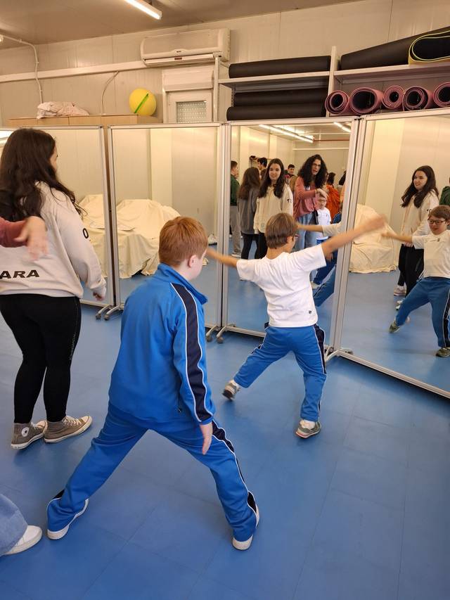 Un grupo de niños y adolescentes participan en una actividad frente a espejos en un aula.