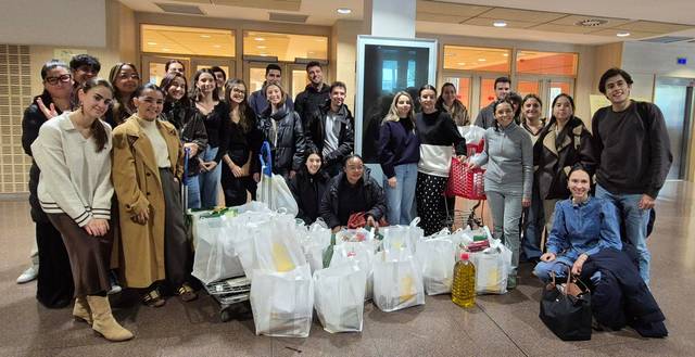Un grupo de personas sonrientes se encuentra rodeado de bolsas de compra en un lugar cerrado.