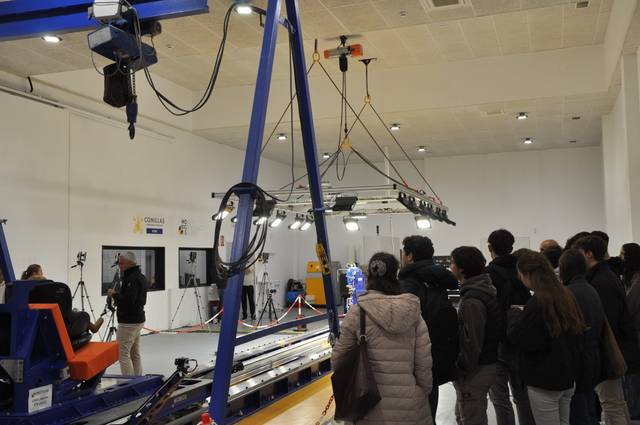 Un grupo de personas observa una demostración de un equipo industrial en un ambiente de trabajo.